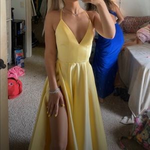Long,yellow, dress that has pockets and a slit down the left leg.